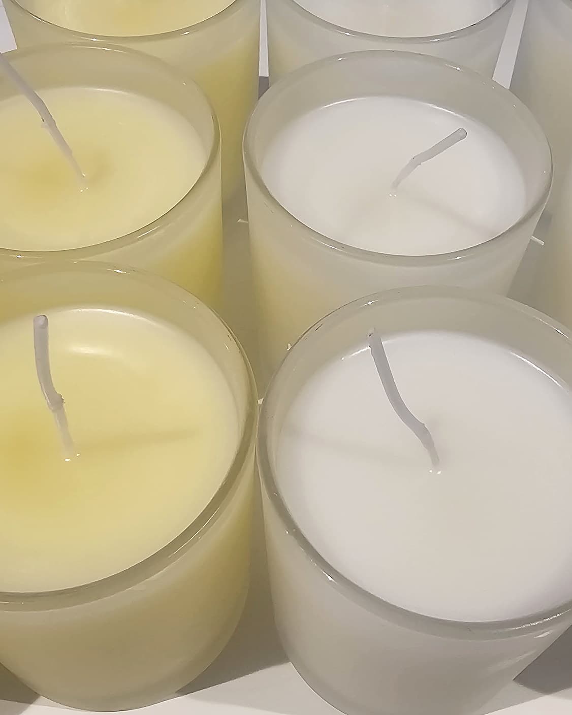 Rows of frosted glass jars freshly poured and setting on a white bench, wicks still untrimmed; the paler, warmer wax at the left is Pomander.