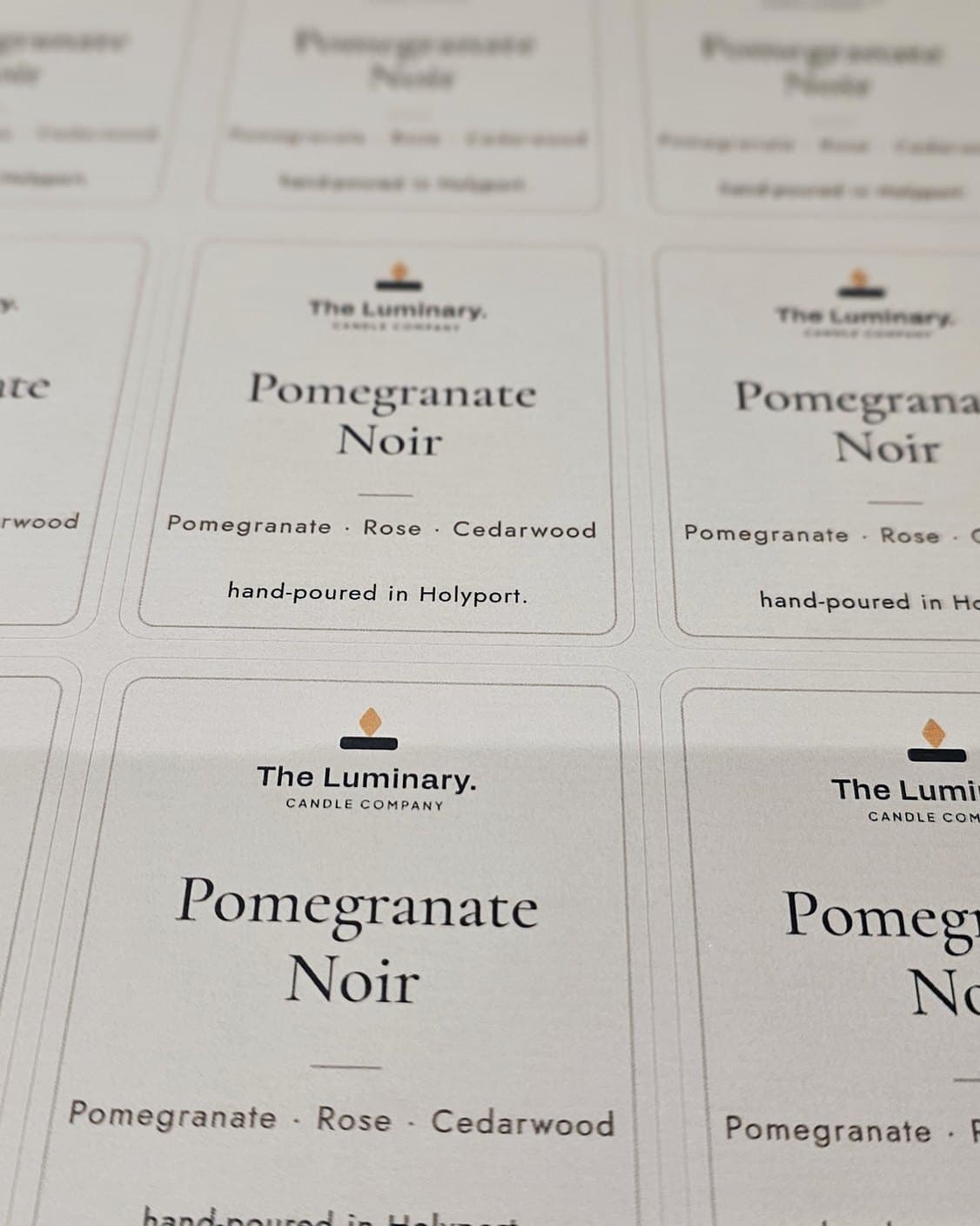 A printed sheet of Pomegranate Noir front labels on textured paper, one in sharp focus.